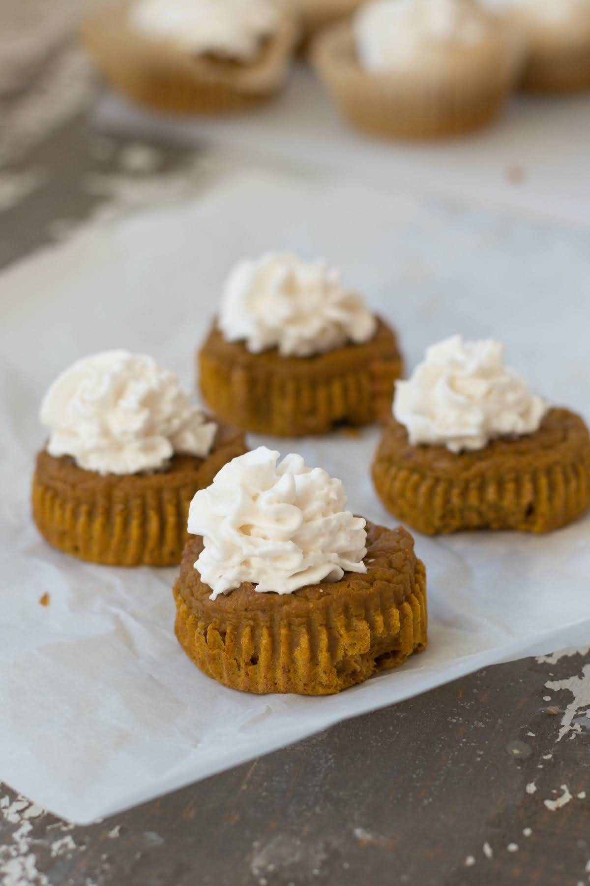four pumpkin pie cupcakes topped with coconut whipped cream.
