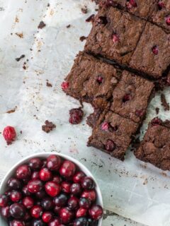 Gluten free brownies next to a bowl of cranberries.