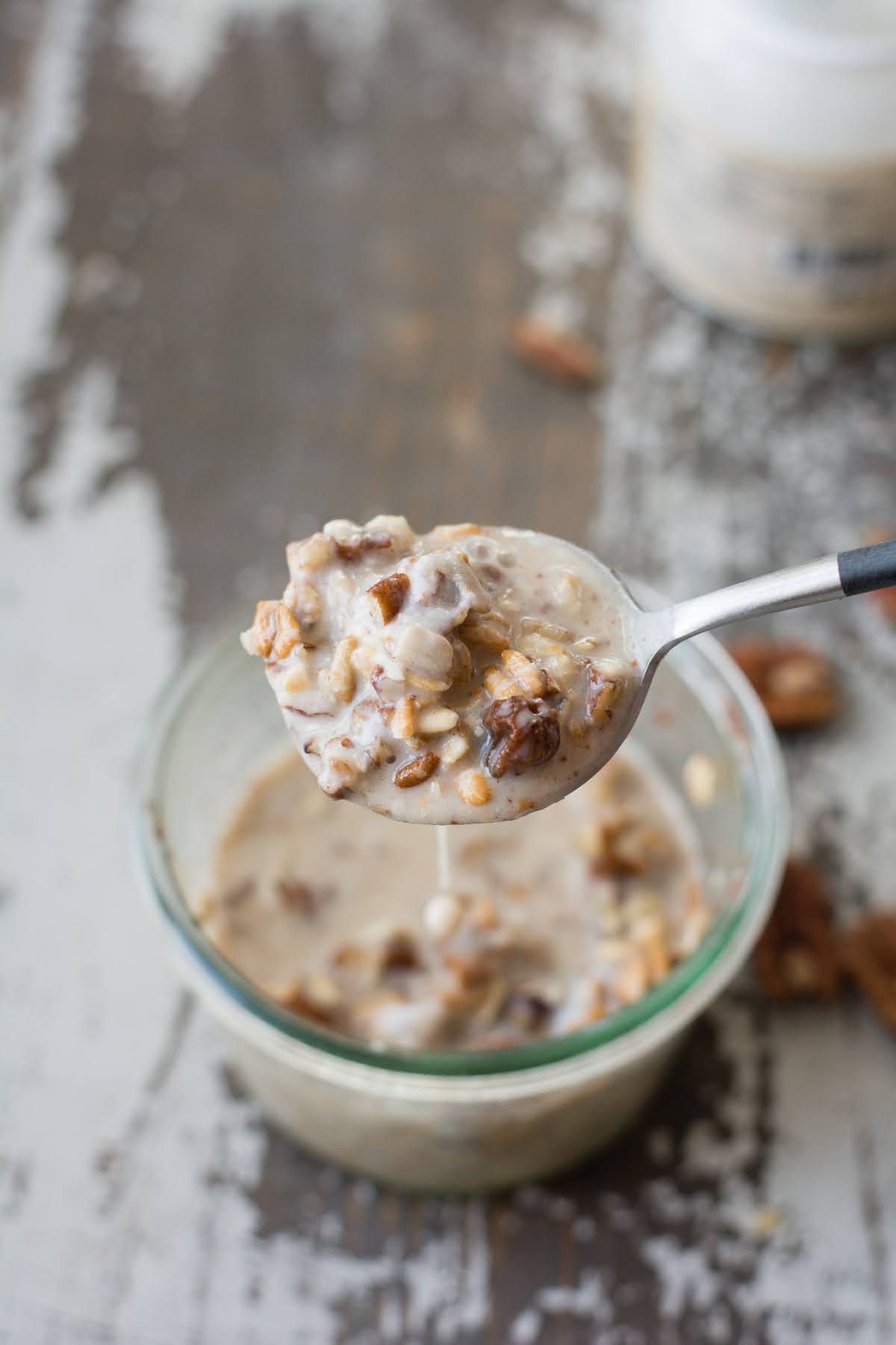 Lifting a spoonful of overnight oats out of a glass jar.