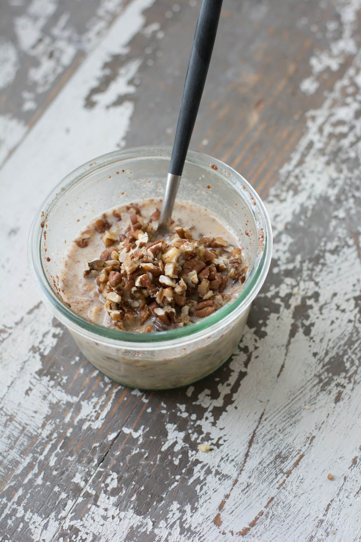 Overnight oatmeal in a glass bowl, with pecan topping.