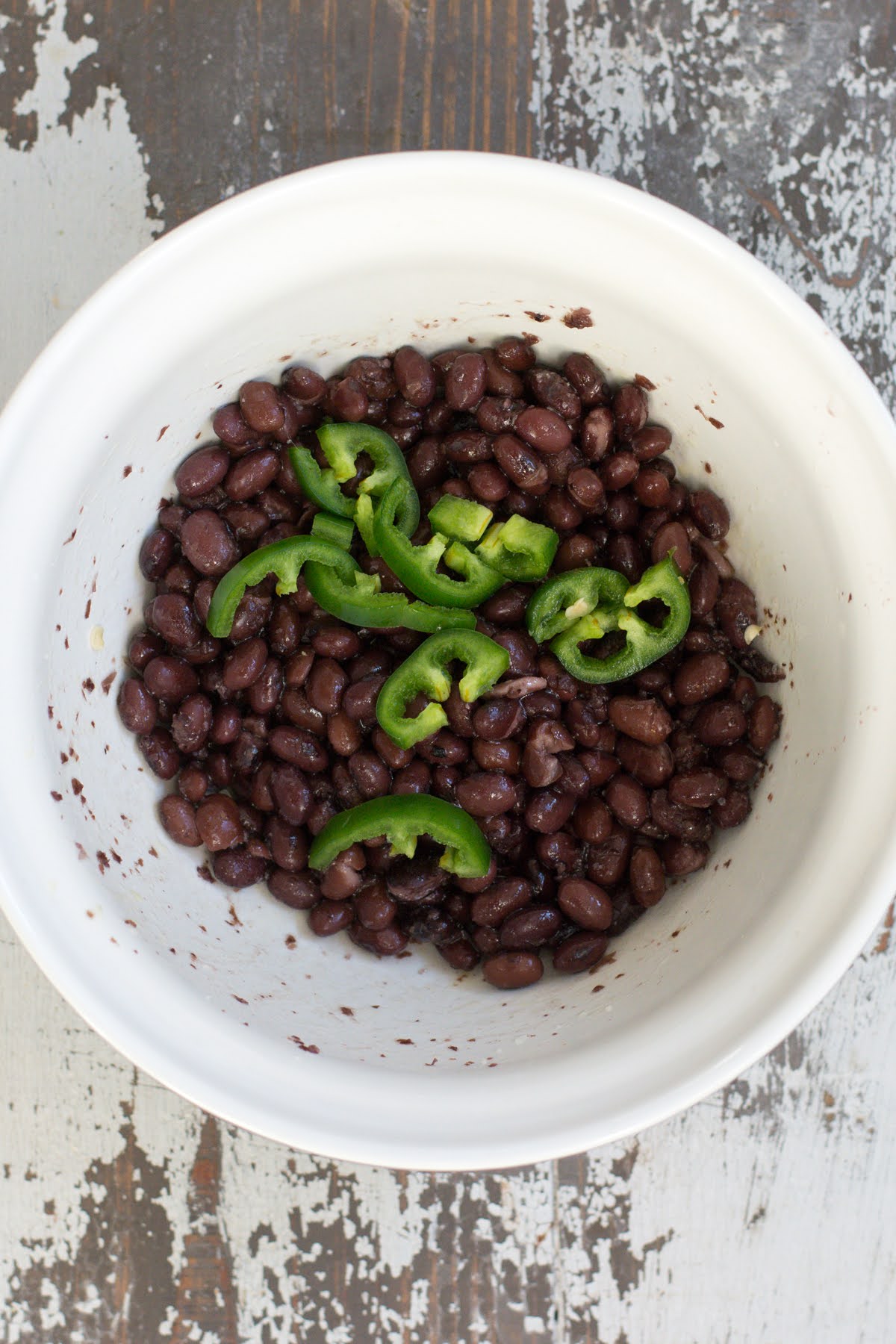 A bowl of black beans with jalapenos.