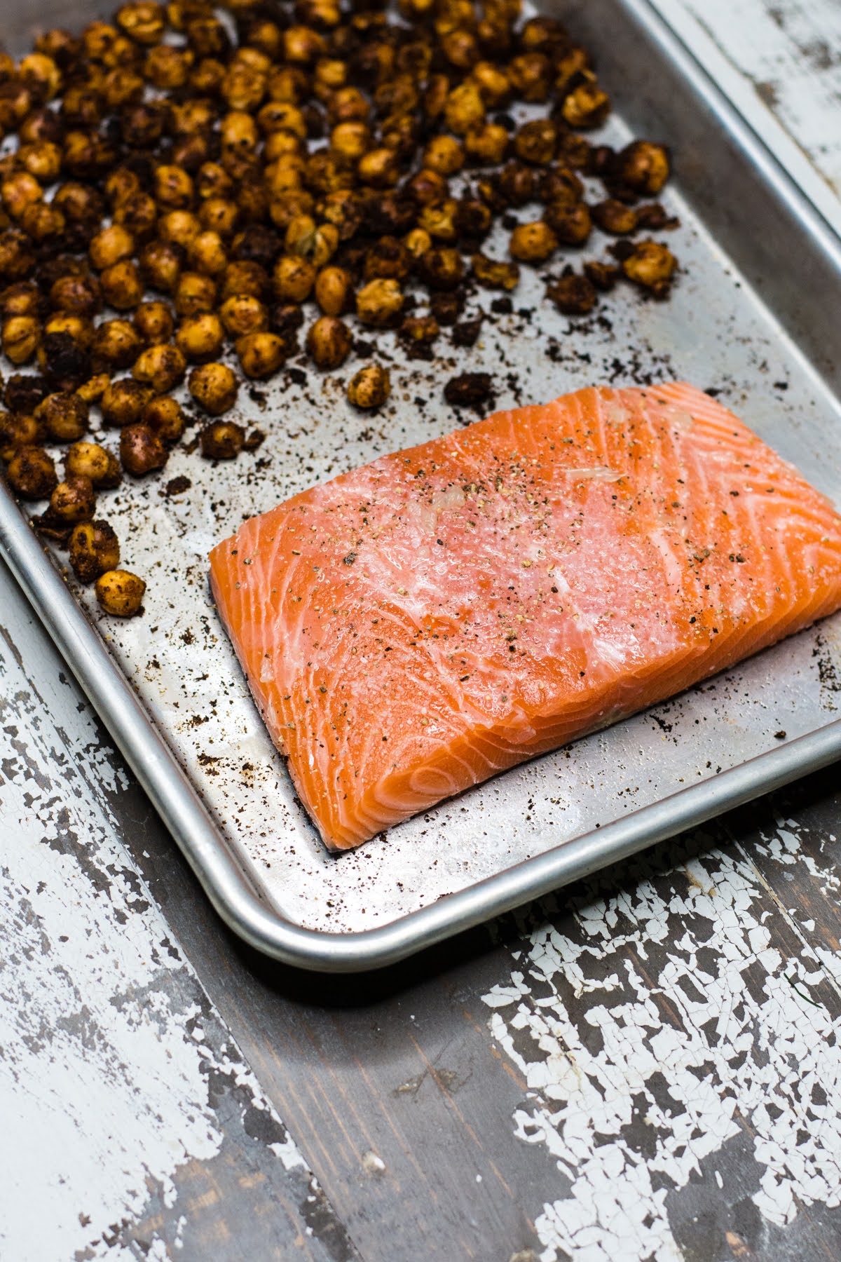 A filet of salmon on a sheet pan with roasted chickpeas.
