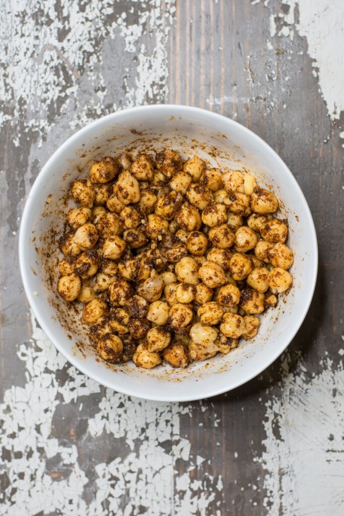 Chickpeas in a bowl with smoked paprika, oil, and other seasonings.