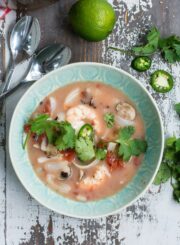 A bowl of Thai soup with shrimp, garnished with cilantro.