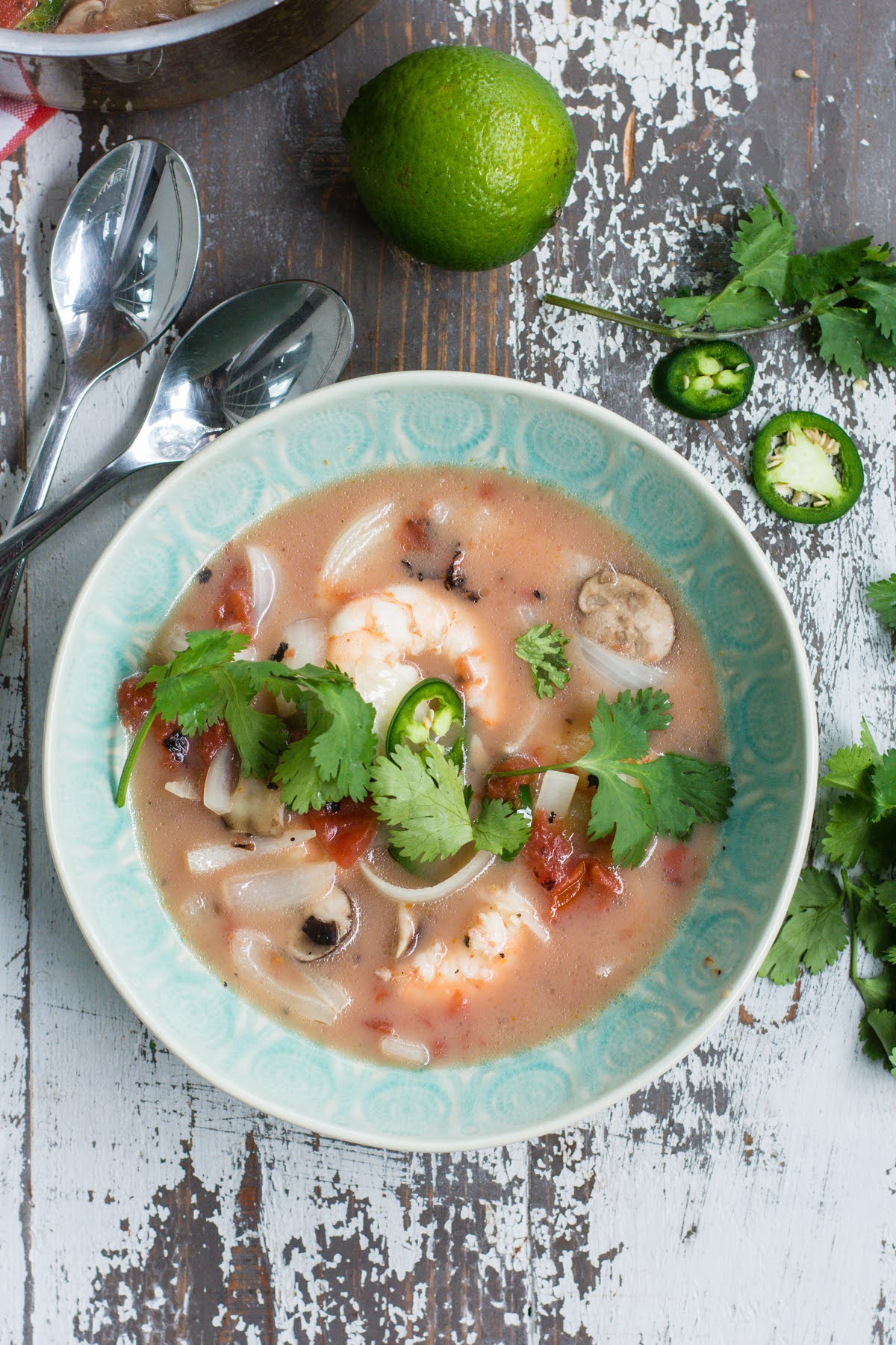 A bowl of Thai soup with shrimp, garnished with cilantro.
