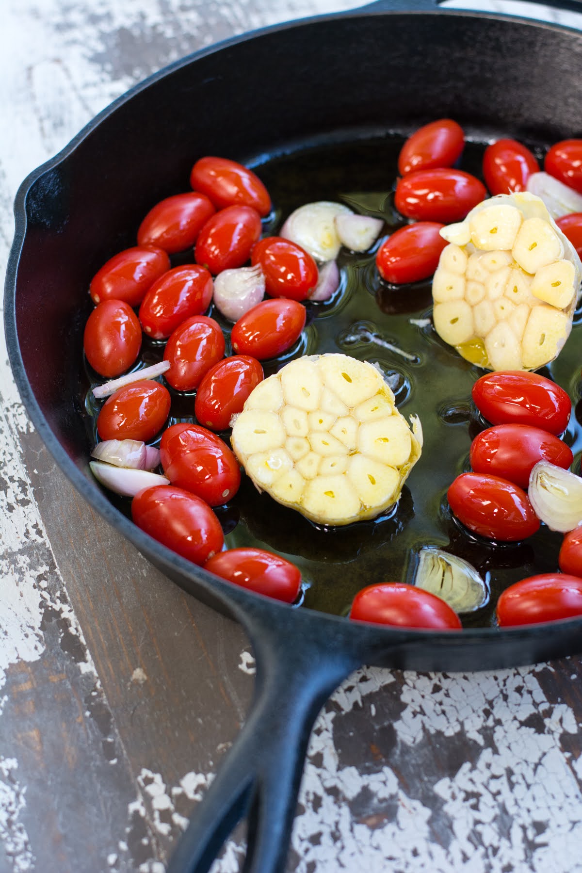 Tomatoes, shallots, and cut heads of garlic in a skillet with olive oil.