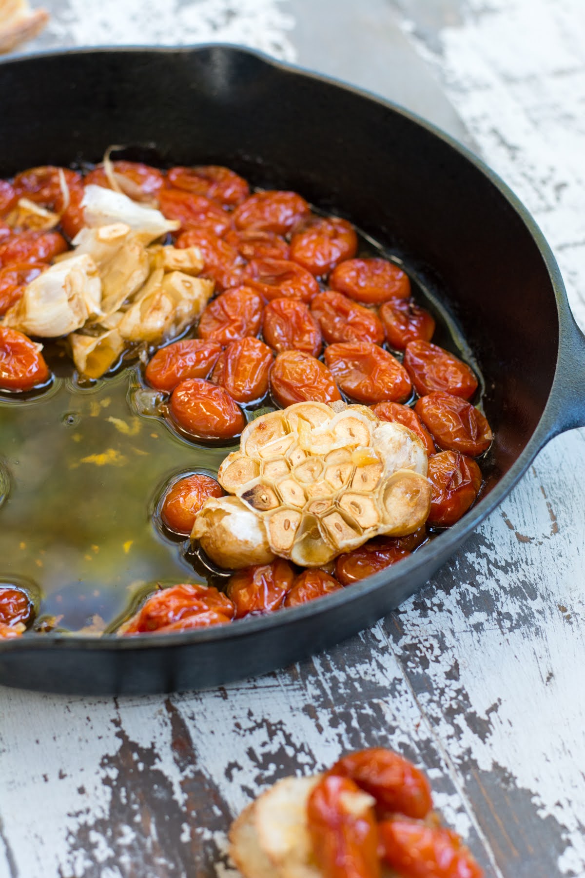 Baked tomatoes in a skillet with roasted garlic.
