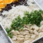 A sheet pan of chicken, rice, beans, and other ingredients.