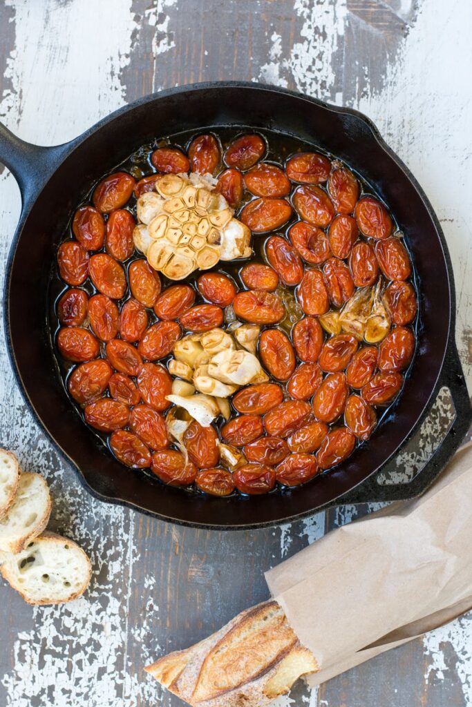 Overhead shot of a skillet of baked tomatoes in olive oil.
