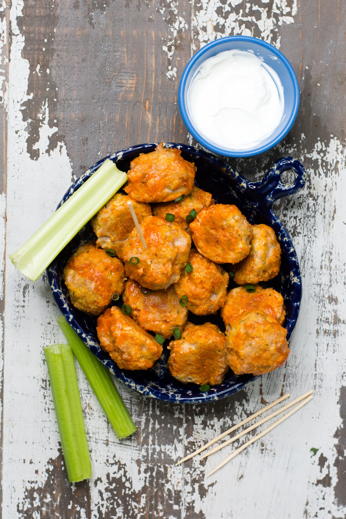 A bowl of buffalo chicken meatballs with celery and ranch.