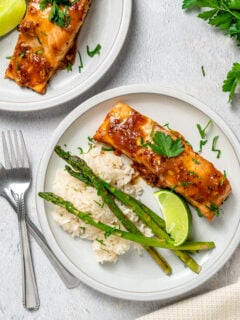 Salmon portions with asparagus and rice on white dinner plates.