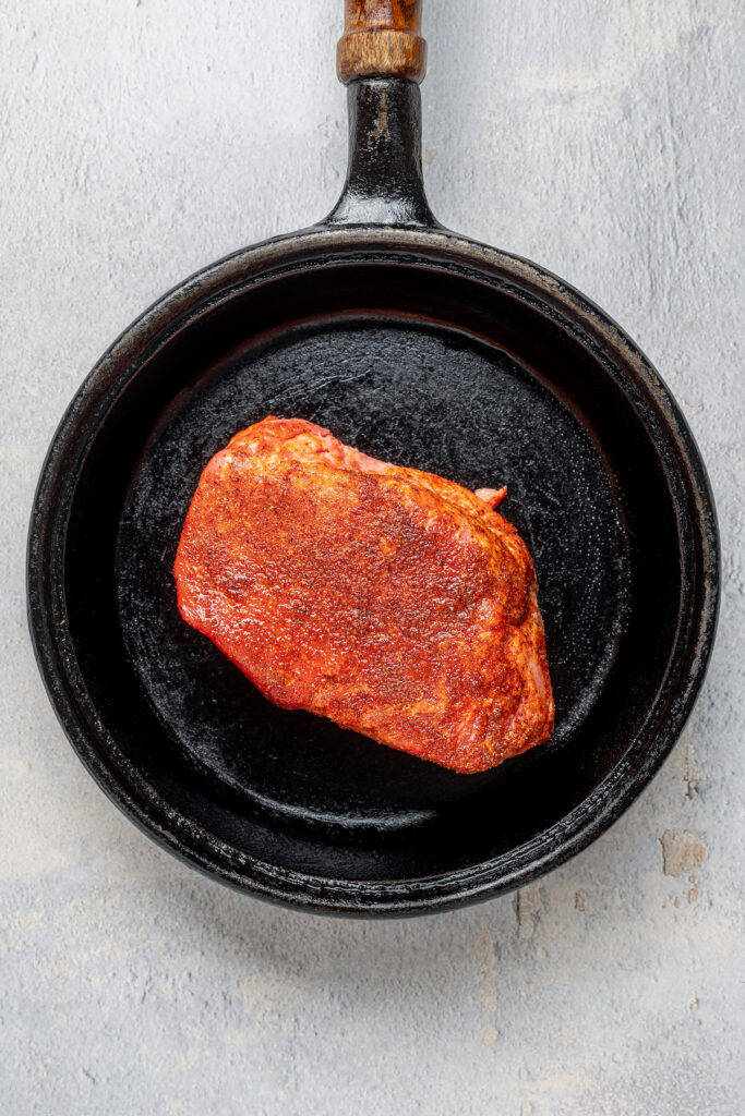Cooking a steak in a cast-iron skillet.