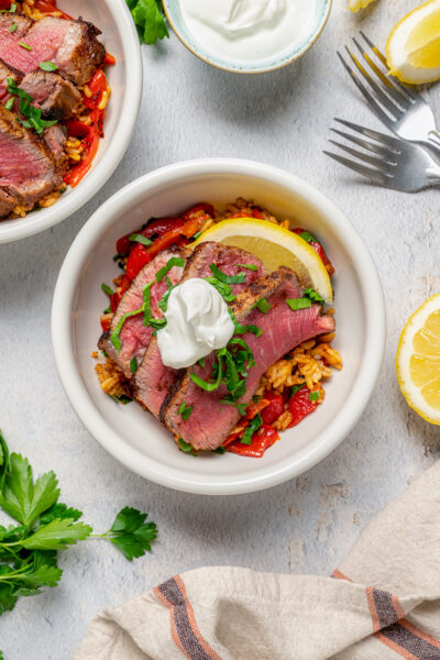 A steak taco bowl garnished with sour cream and parsley.