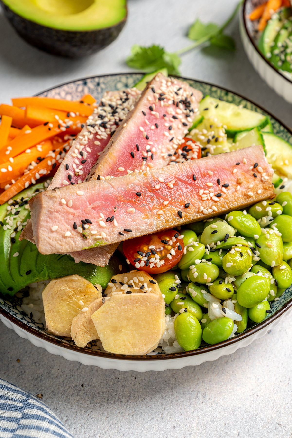 Asian-style sliced tuna in a bowl with rice and toppings.