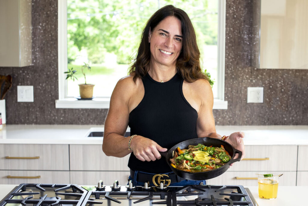 Photo of Amy holding a skillet filled with healthy food in a kitchen