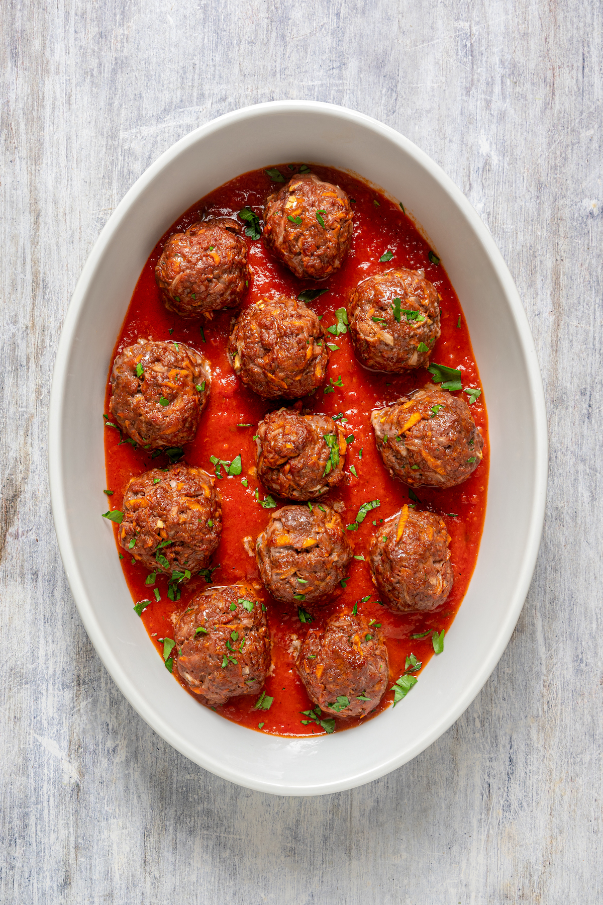 An oval baking dish with meatballs and sauce.