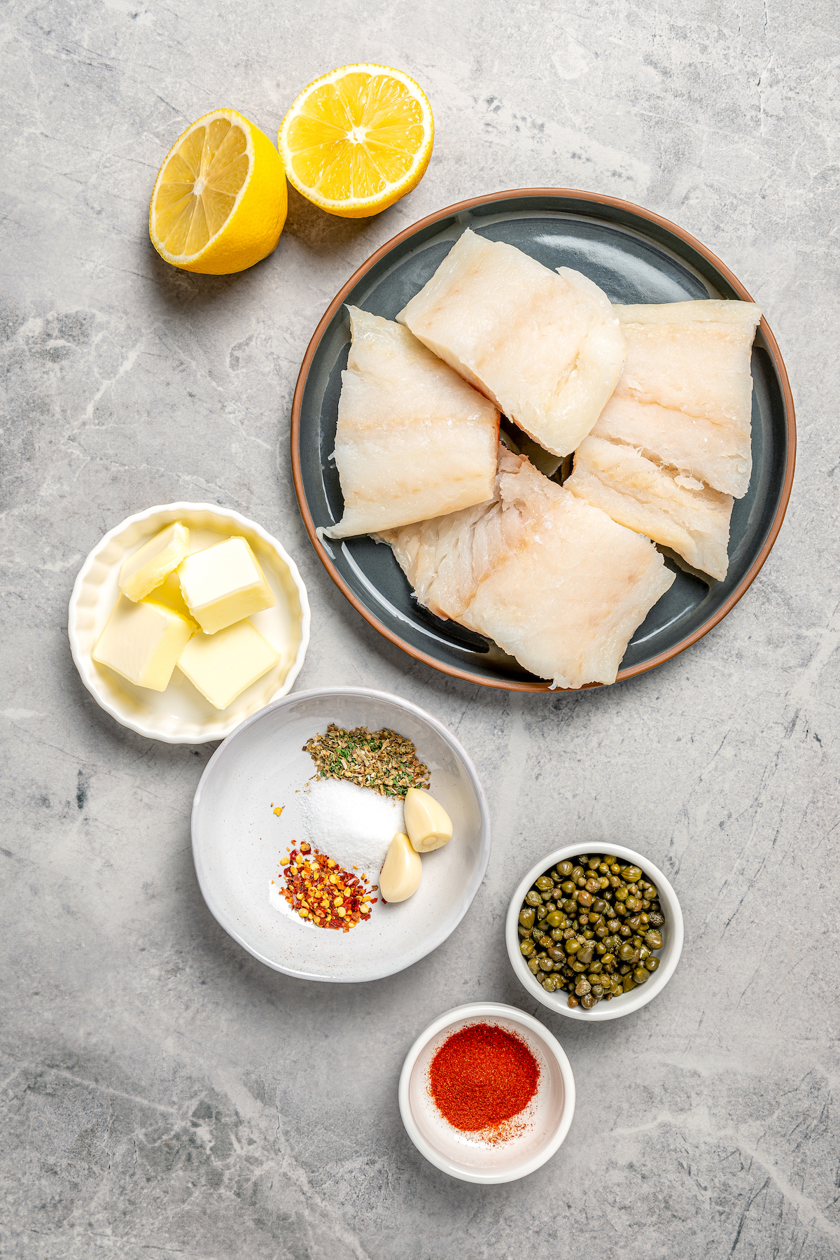 Ingredients for a simple baked cod recipe, measured and arranged on a table.