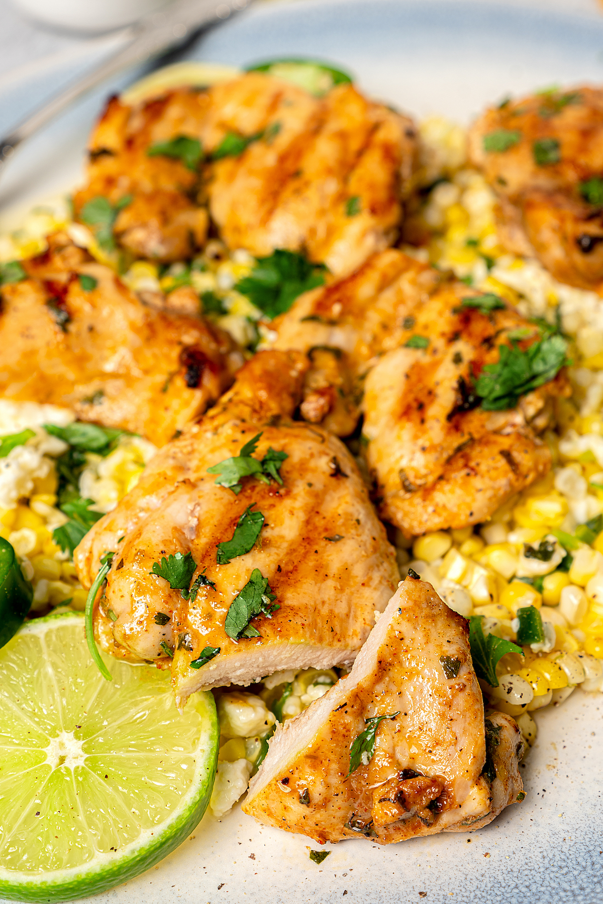 Chicken and Mexican street corn garnished with lime slices and cilantro.