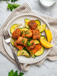 An air fryer salmon recipe served on a white plate with a cloth napkin.