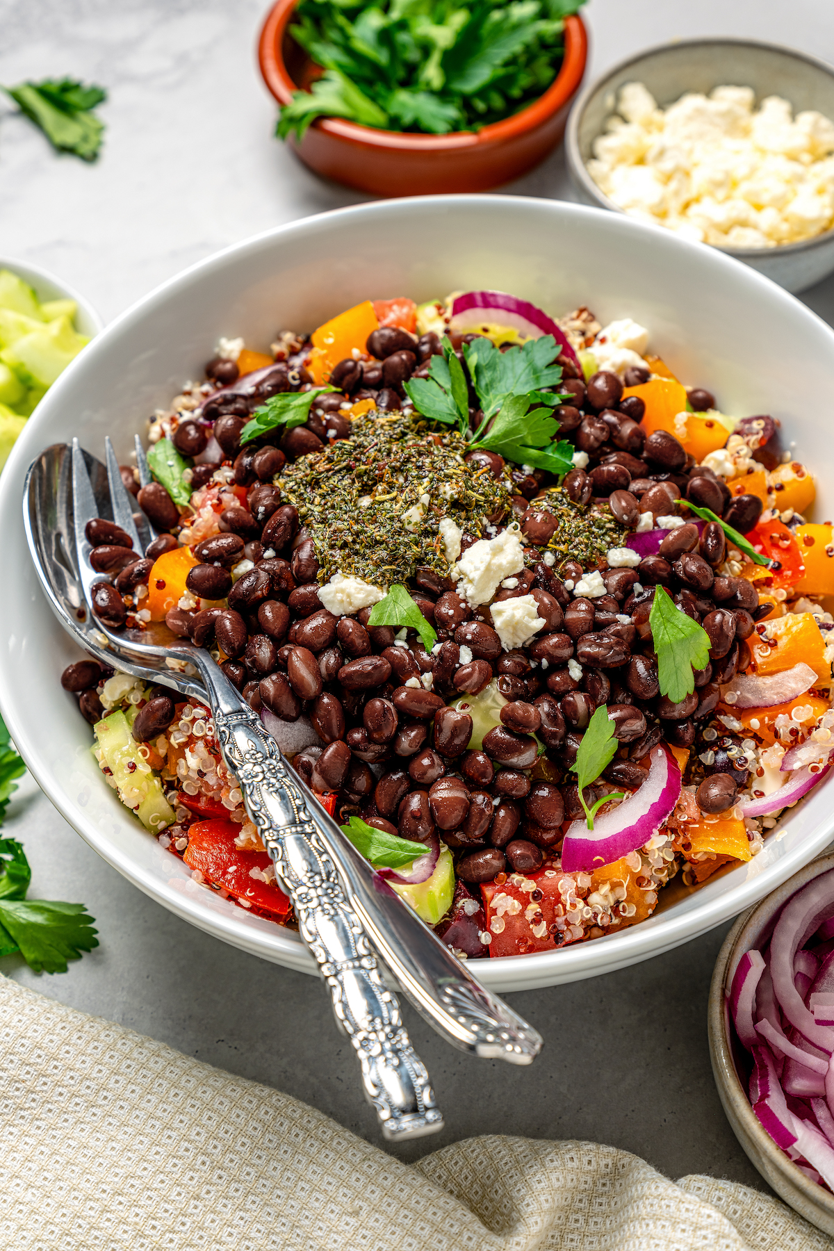 Utensils resting in a serving bowl of black bean quinoa salad.