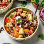 A bowl of healthy Greek salad made with black beans and ancient grains.