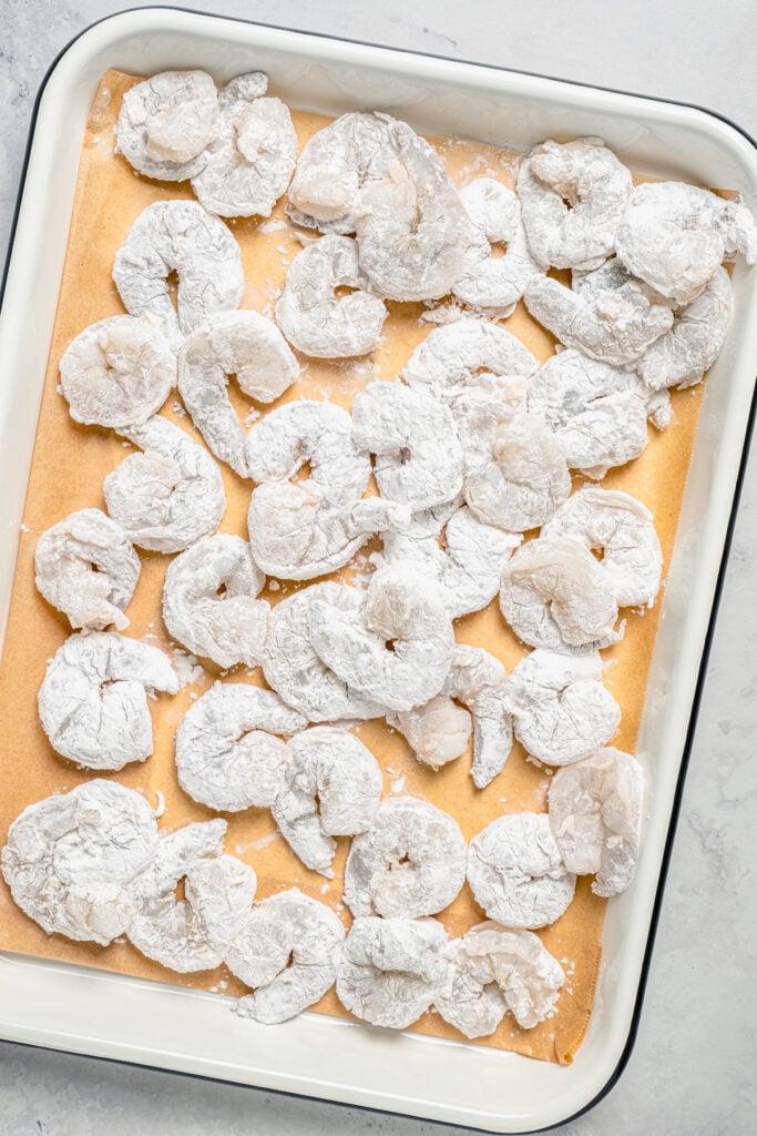 Cornstarch-coated shrimp on a baking sheet. 