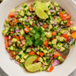 Bowl of shirazi salad with lime wedges.