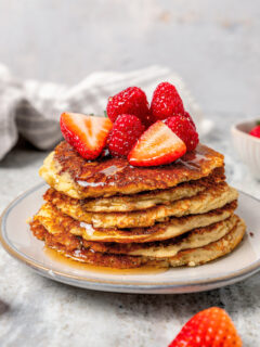 Stack of protein pancakes with fresh strawberries on top.